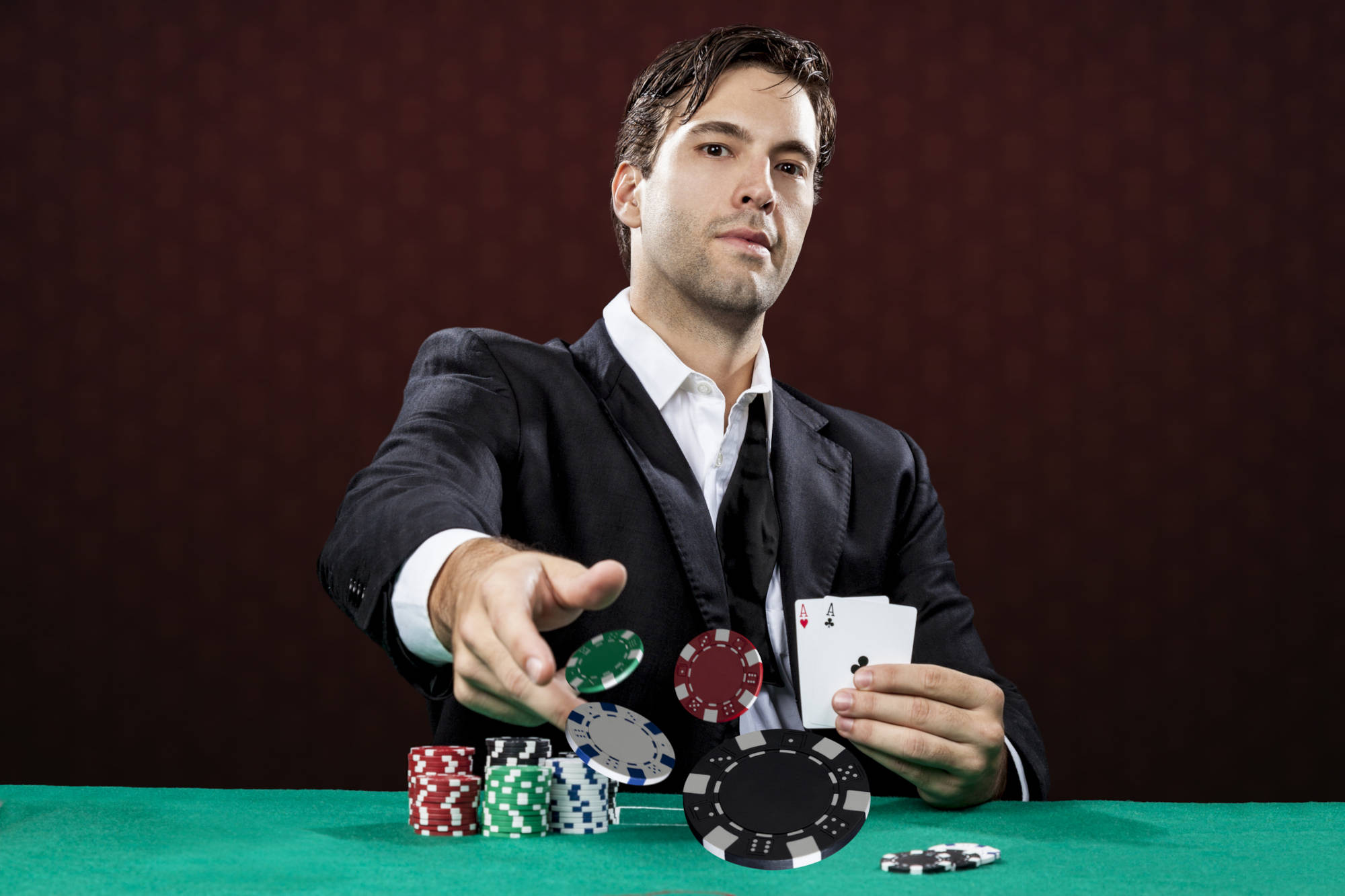 Poker player, on a red background, throwing poker chips.