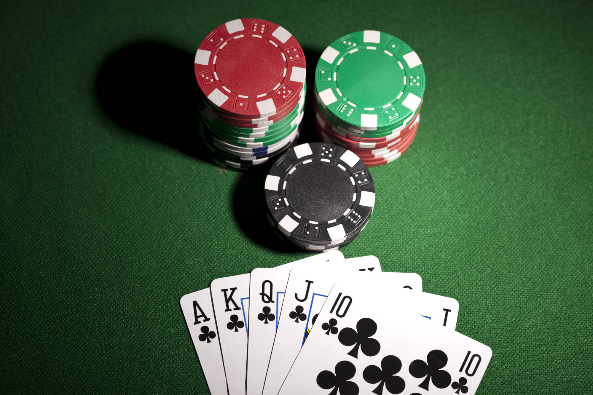 Royal flush and gambling chips on green background.