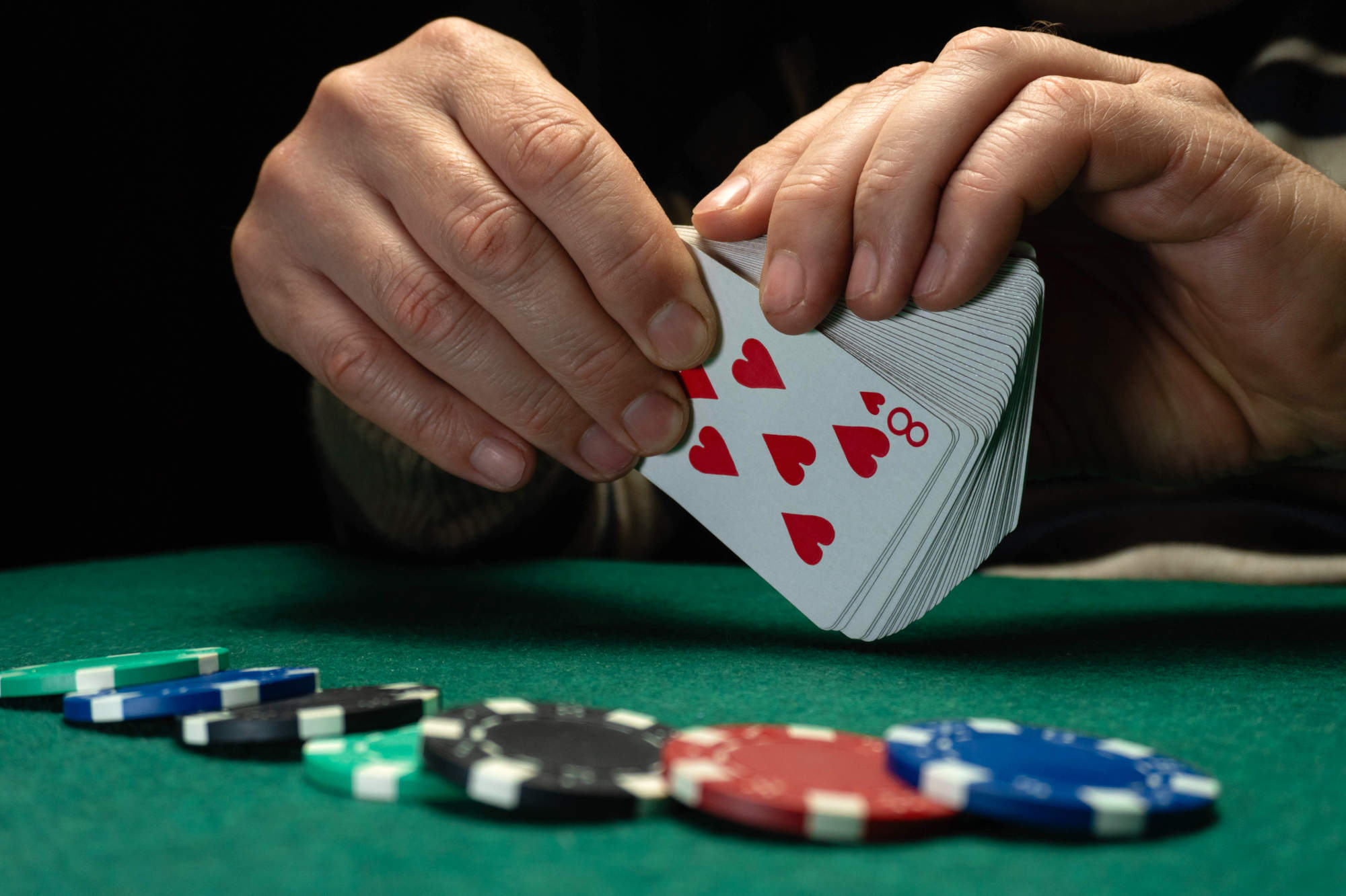 A person holds a deck of playing cards and prepares to deal in a poker game.