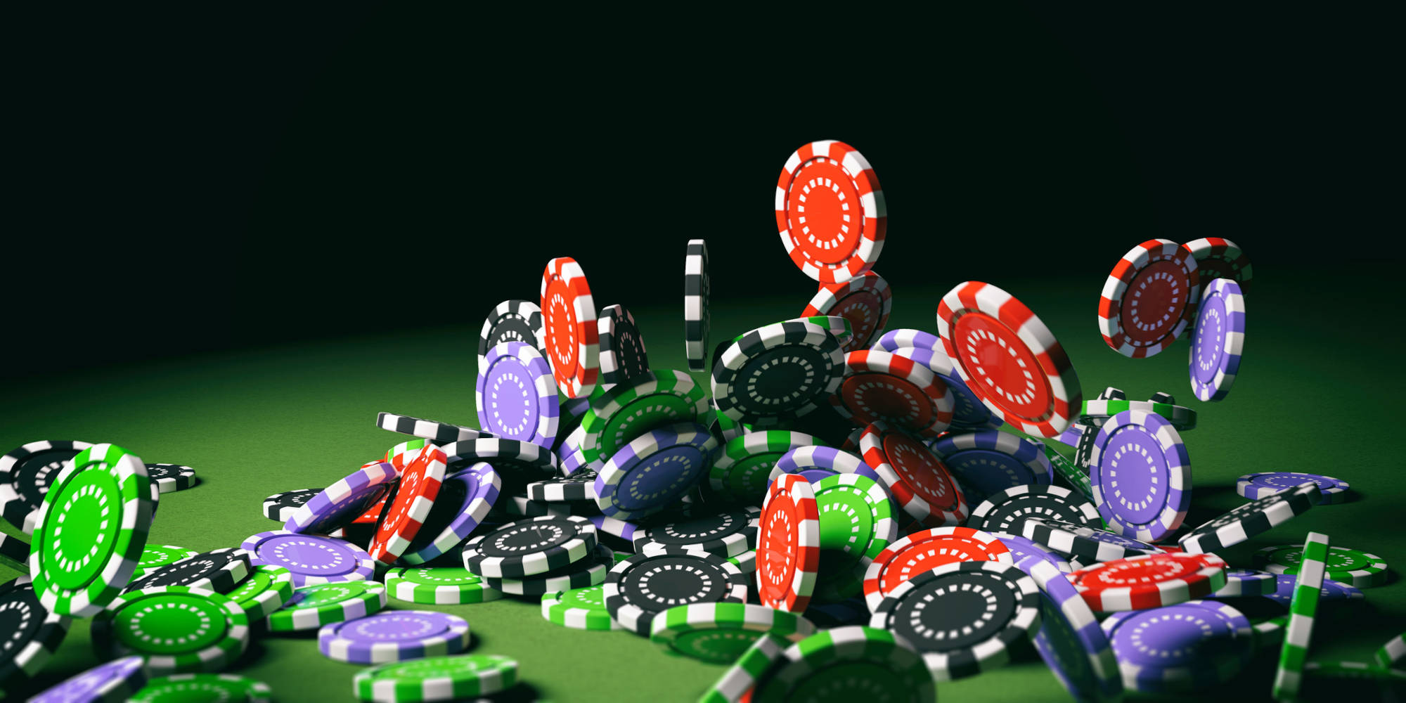Colorful poker chips falling on green felt background.